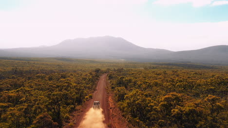 aerial view of a vehicle driving on a dirt road through a desert landscape