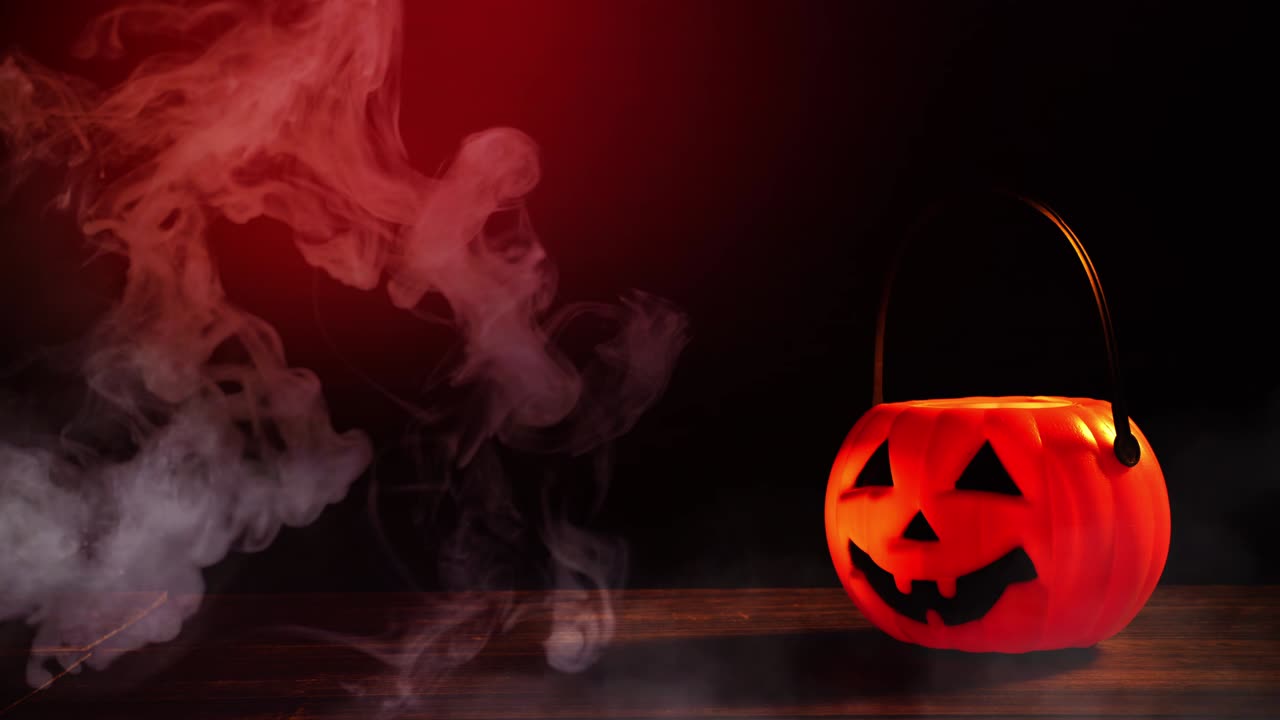 concepto de halloween - linterna de calabaza de plástico naranja en una mesa de madera oscura con humo alrededor del fondo, truco o regalo.