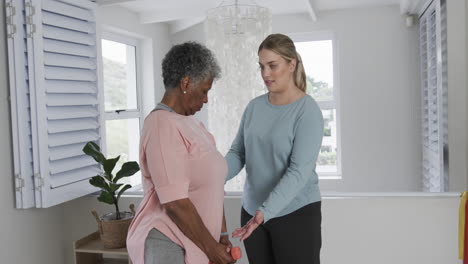 caucasian female physiotherapist with senior woman exercising, copy space, slow motion