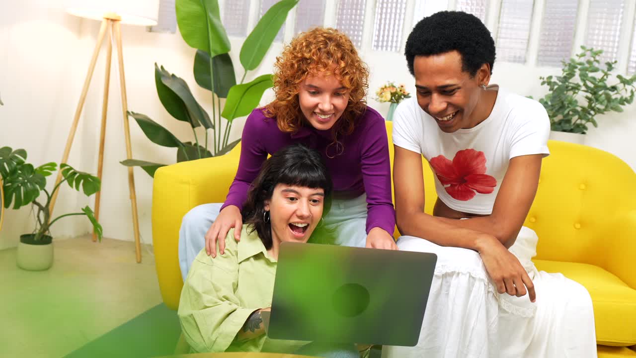 Three people looking at a laptop on a couch
