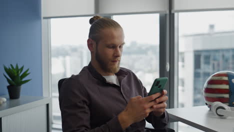 focused youngster using mobile phone in flat closeup. calm man reading messages