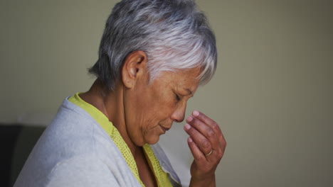 Senior-mixed-race-woman-with-headache-sitting-touching-brow