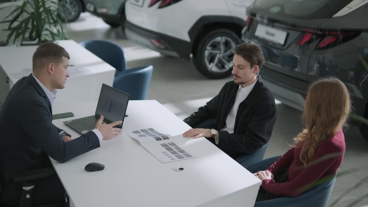 Customers meeting with salesman at a car dealership