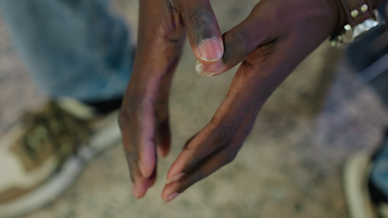 Close up overhead of dark skin person tapping hands together while wearing wristwatch standing in casual outfit on granite floor indoor space focusing on detail gesture