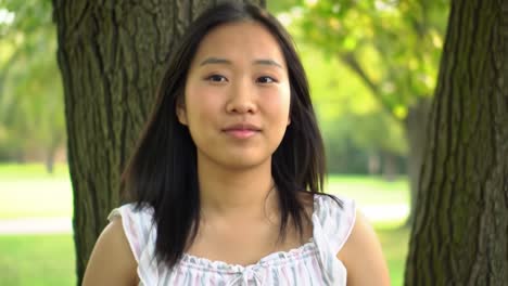 a tranquil moment: a young woman embraces nature's serenity while standing beneath the trees, expressing peace and inner calm in a subtle, reflective pose