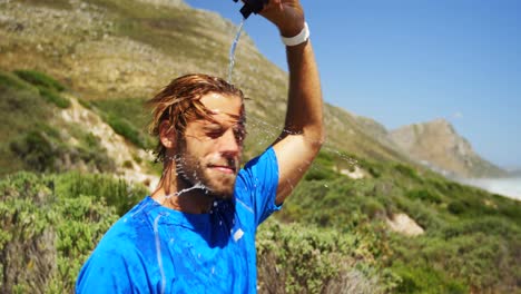 hombre triatleta vertiendo agua en su cara en un día soleado