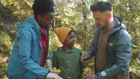 kid helping parents with collecting trash after camping