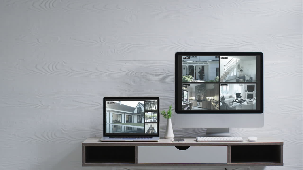 Wall mounted computer monitor and laptop on desk with security camera views on screens, slow motion