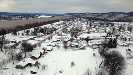 Aerial-view-of-city,-mountains-and-river-covered-in-snow