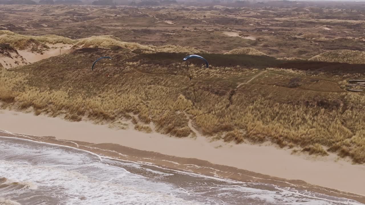 Aerial view of a beach with sand dunes and kite flying