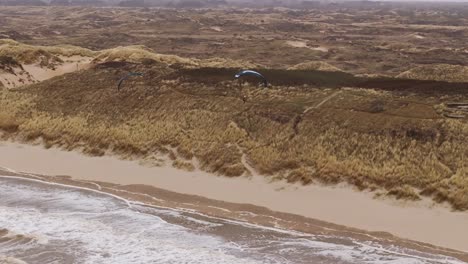aerial view of a beach with sand dunes and kite flying