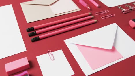 close up of pens, pencils and stationery arranged on red background, in slow motion