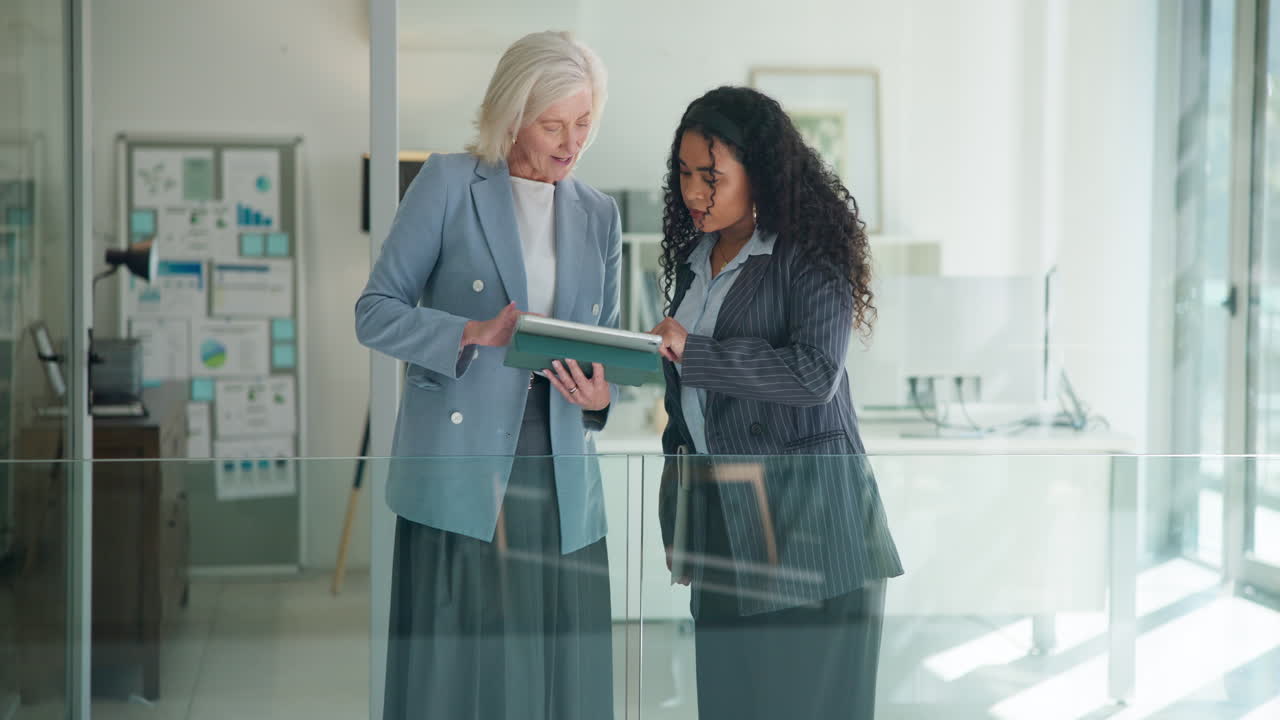 Two Businesswomen Discussing Work on a Digital Tablet in Modern Office