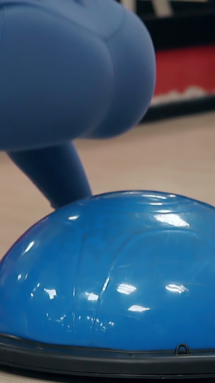 slow motion close back view girl in blue leggings and white sneakers jumps and sit-ups on stability ball in sport club