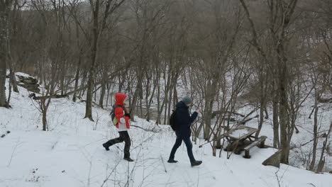 young couple walking with backpacks in winter forest