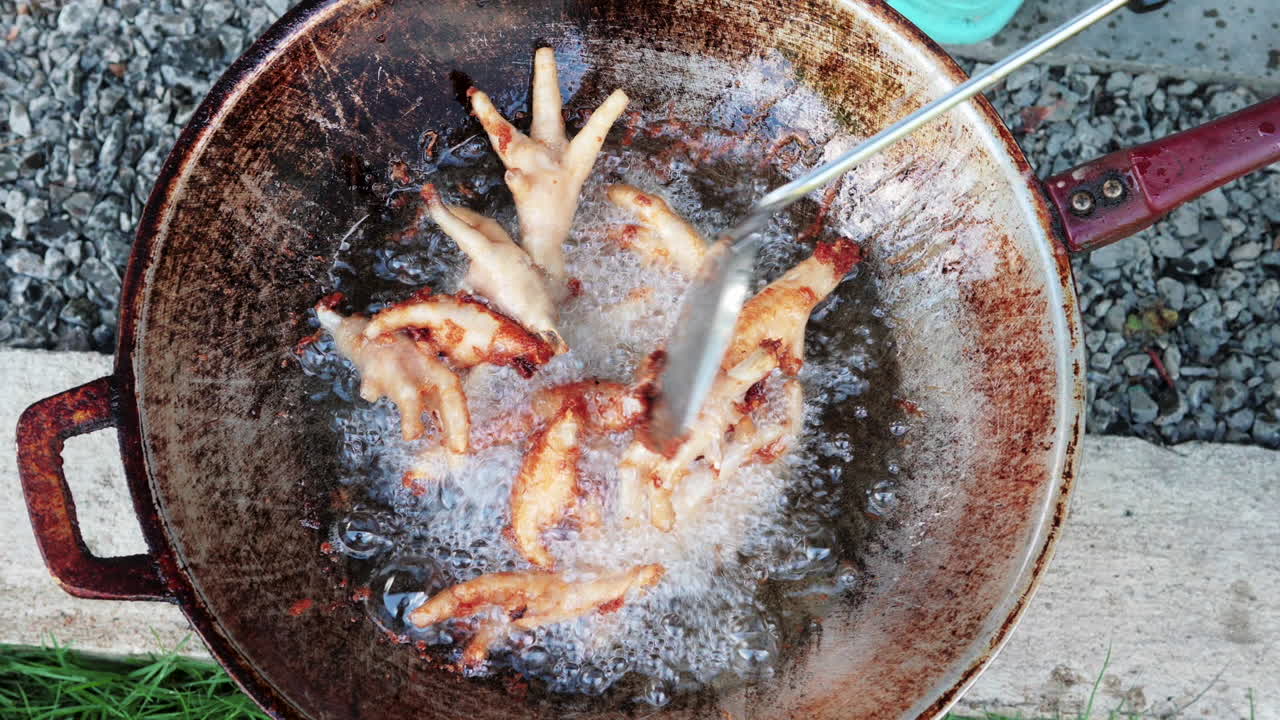 Golden crispy chicken foots stir on by spatula frying pan - shot from above
