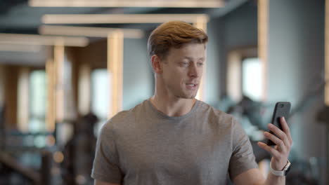 cheerful sportsman saying hi in gym. smiling athlete man having video call