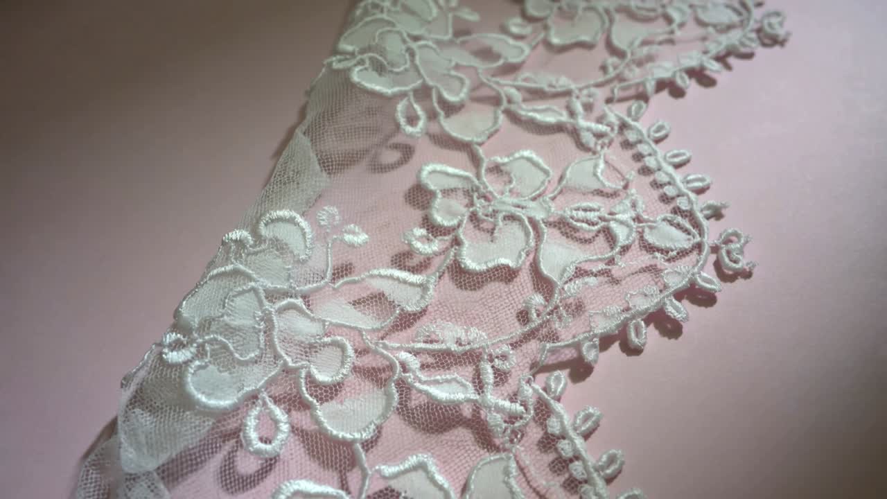 Shifting light from left revealing subtle shadows on white lace trim at table, with satin motifs