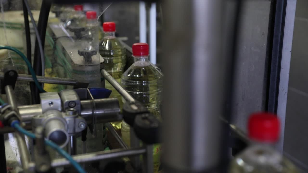 Plastic Bottles Filled with Vinegar on a Conveyor Belt Moves Along to be Prepared for Packaging in a Factory Processing Plant