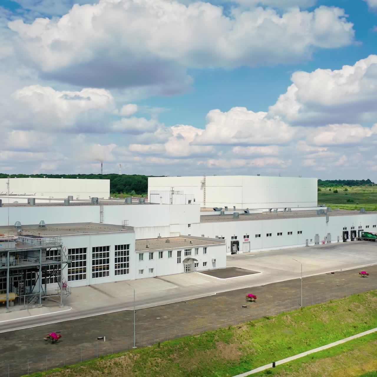 Harmful factory in rural place. Modern industry near the road on green nature background. Large industrial plant on field