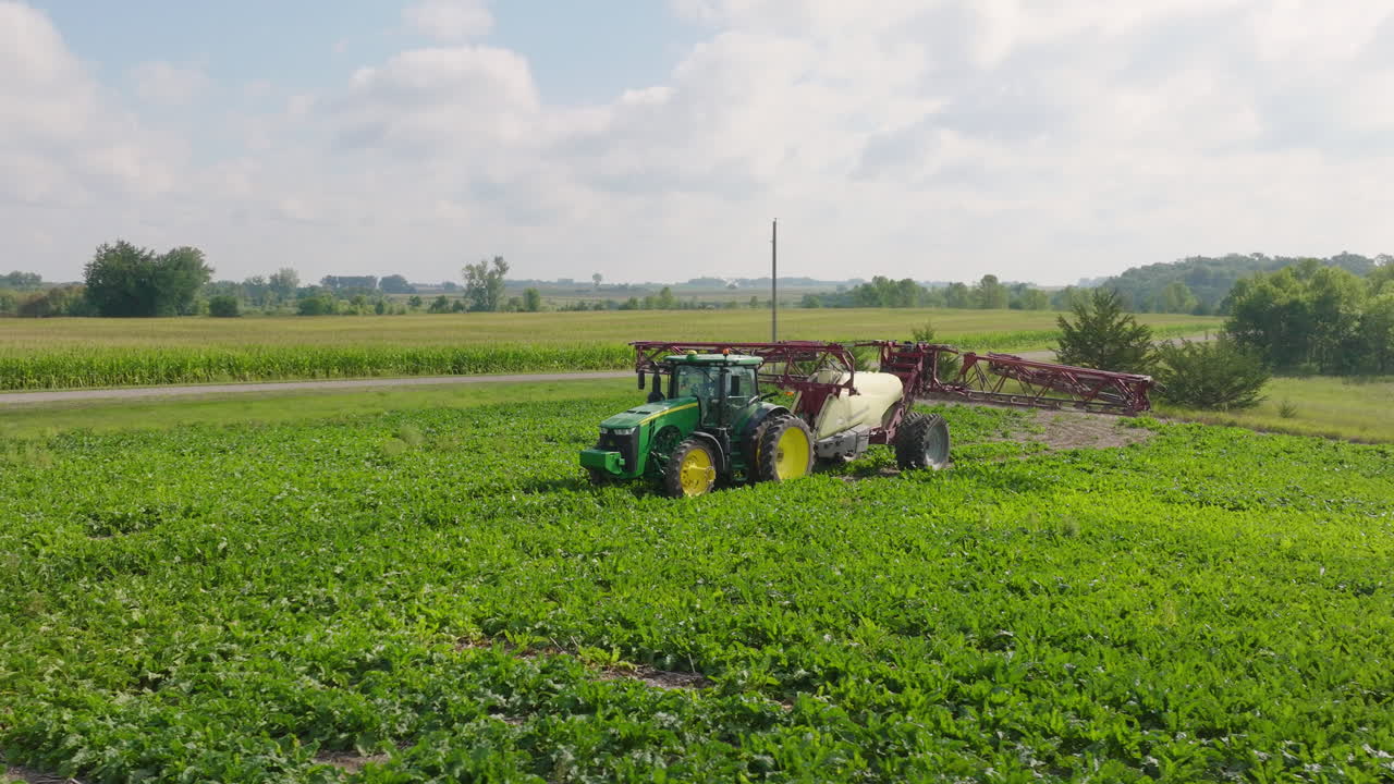 tractor que se prepara para desplegar pulverizadores de brazo extendido para la aplicación de plaguicidas en el campo agrícola