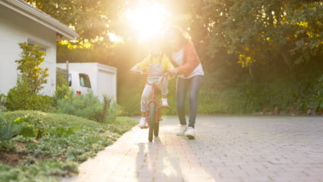 mother, kid and learning to ride a bicycle at home