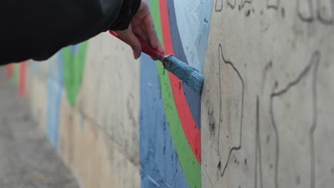 person painting a mural on a concrete wall