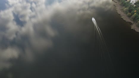 Aerial-high-altitude-shot-of-the-motorboat-riding-fast-on-the-calm-dark-waters-in-northern-Europe