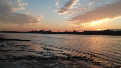 silhouette of city buildings on river schelde coastline, aerial side fly view