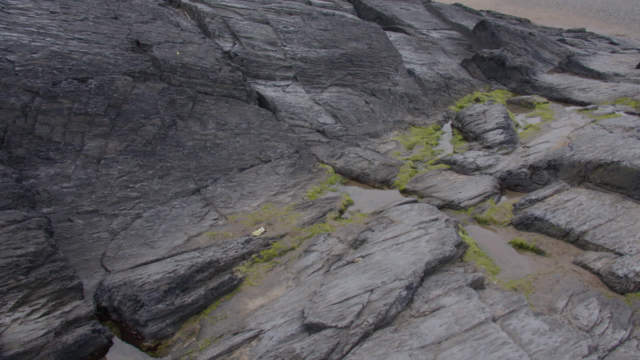 Panning shot left to right of sedimentary rocks at low tide at Tresaith beach