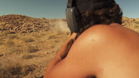 View-of-a-guy-shooting-while-target-practicing-with-a-hunting-rifle-at-targets-on-the-shooting-range-by-the-outskirts-of-Pleasant-Valley,California,USA-on-a-sunny-afternoon