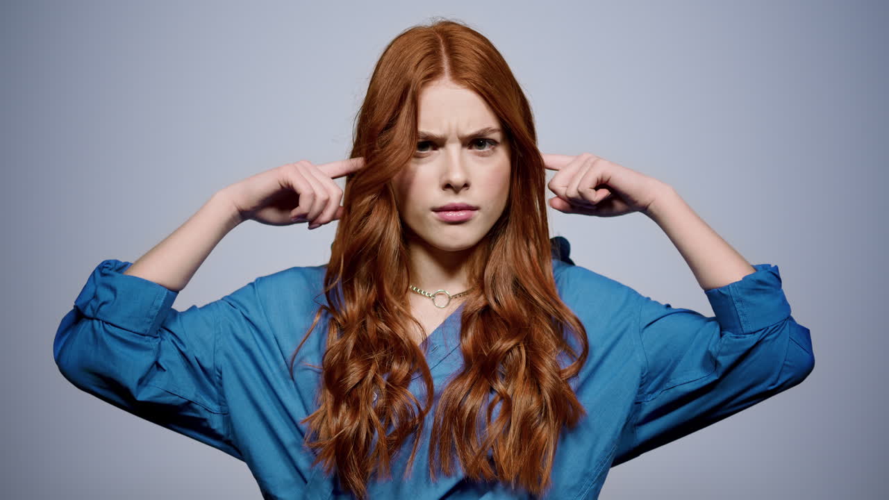 집 안에서 머리를 흔들고 있는 흥분된 소녀. 스튜디오에서 귀에 손가락을  ⁇ 는 여자