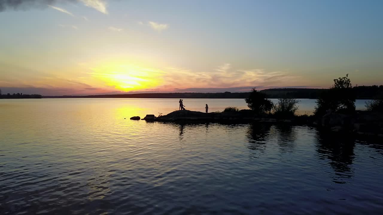 People relaxing on a river bank, enjoying the riverside sunset