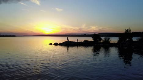 people relaxing on a river bank, enjoying the riverside sunset