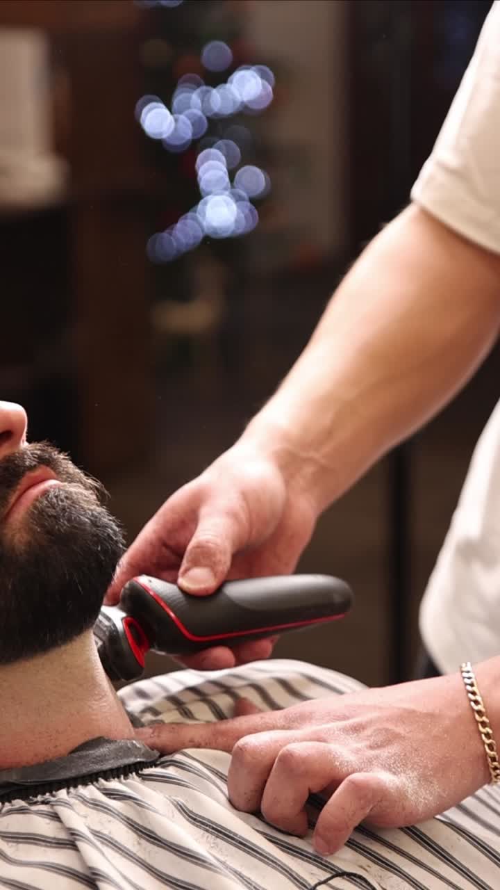 Nærbillede af en barber, der barberer en mand med en elektrisk shaver
