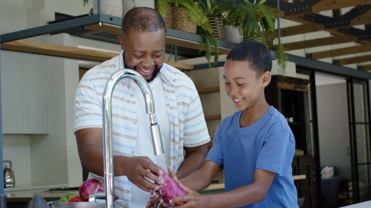 Father and child switching faucet, guiding son rinsing red onions while cleaning at kitchen sink