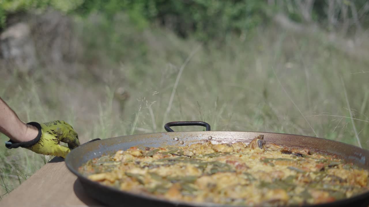 Person preparing traditional paella outdoors