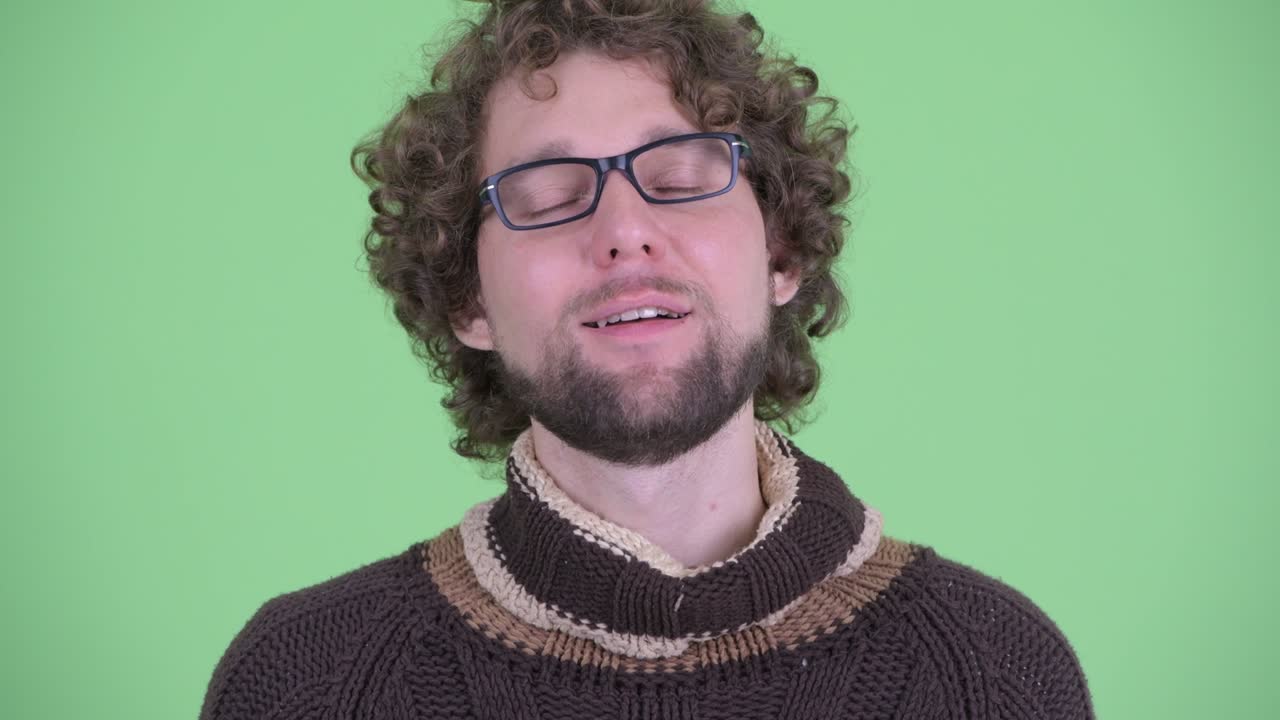 un joven guapo con barba y cabello rizado.