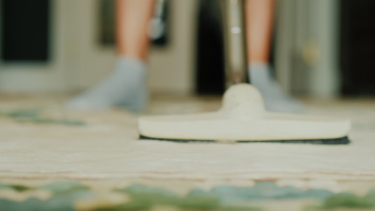 필드의 깊이가 얕은 집 비디오에서 카펫을 진공 청소기로 청소하는 여자