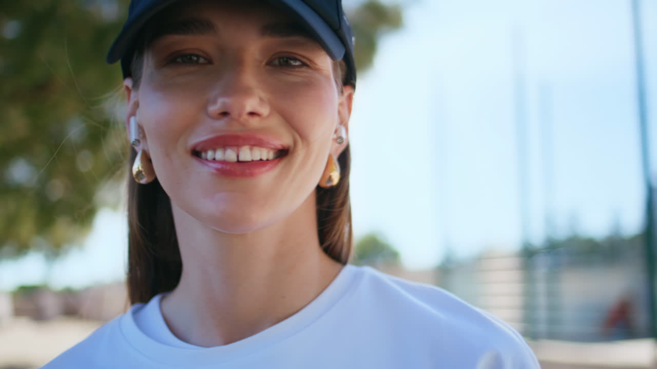 Closed eyes woman listening music earbuds smiling in camera at street closeup