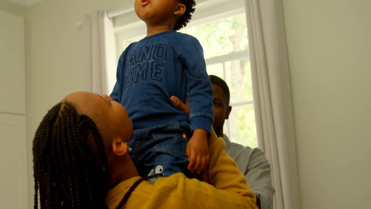 Rear view of young black mother playing and holding her son in a comfortable home 4k