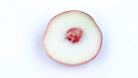 top view from above. one half of a doughnut flat peach with a pit. rotating on the turntable isolated on the white background. close-up. macro.