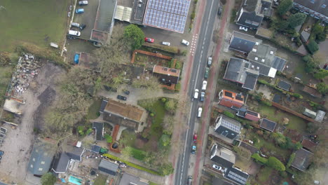 Top-down-aerial-of-a-car-driving-over-road-through-a-beautiful-small-town