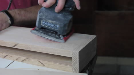 Finish-sanding-the-wood-filler-on-wooden-floating-shelves-in-preparation-to-be-stained-and-hung-in-a-remodeled-bathroom