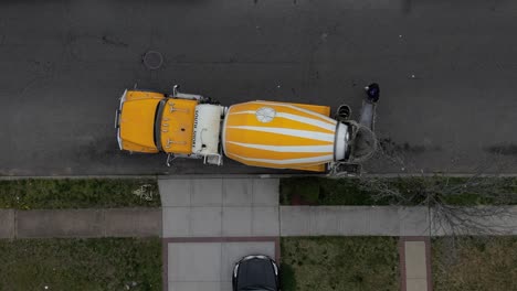 a top down view over a yellow and white cement truck in a residential neighborhood on a cloudy day