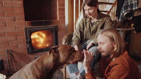 man sitting with wife in farmhouse and petting dog