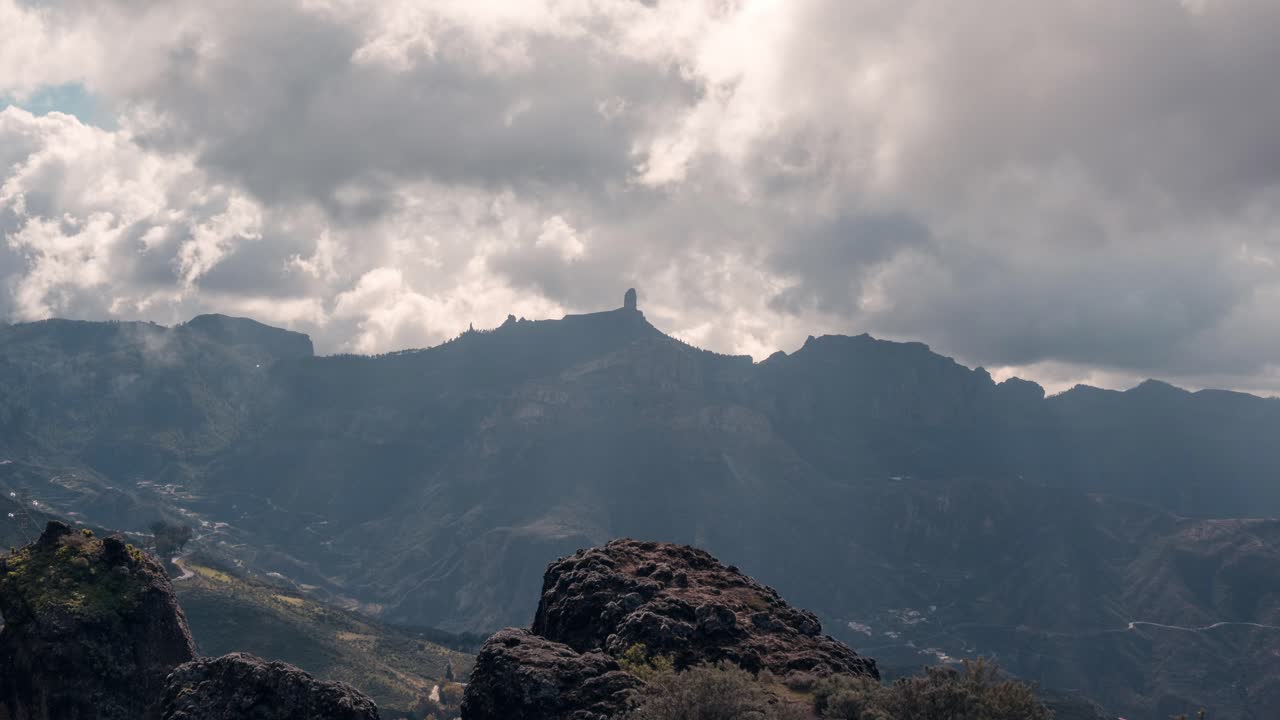 Dramatic timelapse of Roque Nublo silhouetted against a cloudy sky. The iconic volcanic rock stands tall as clouds drift by. Perfect for nature, travel, and atmospheric projects.