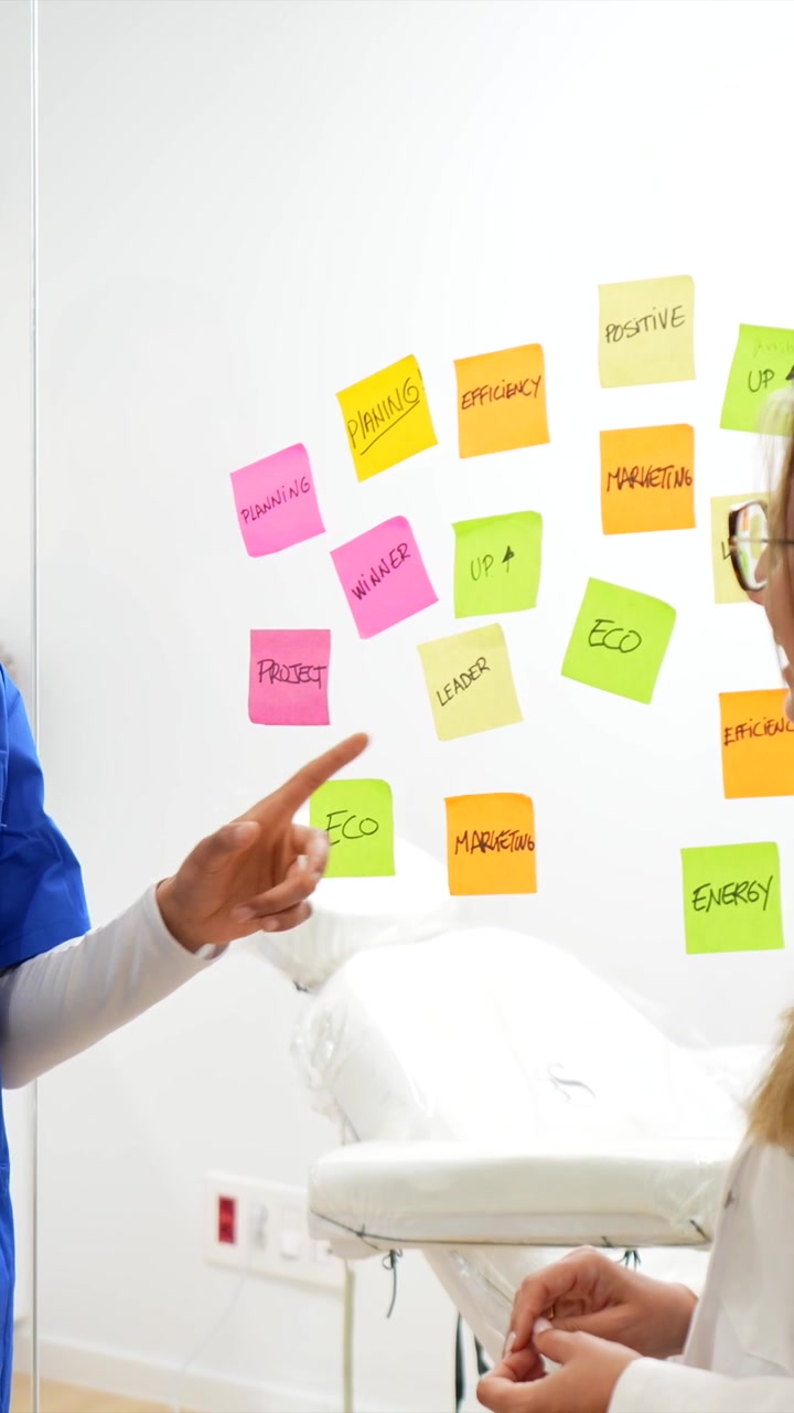 Professionisti medici che discutono la strategia usando post-it su una superficie di vetro