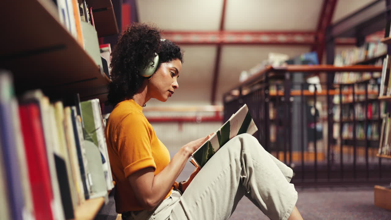 Femme lisant un livre avec des écouteurs dans une bibliothèque