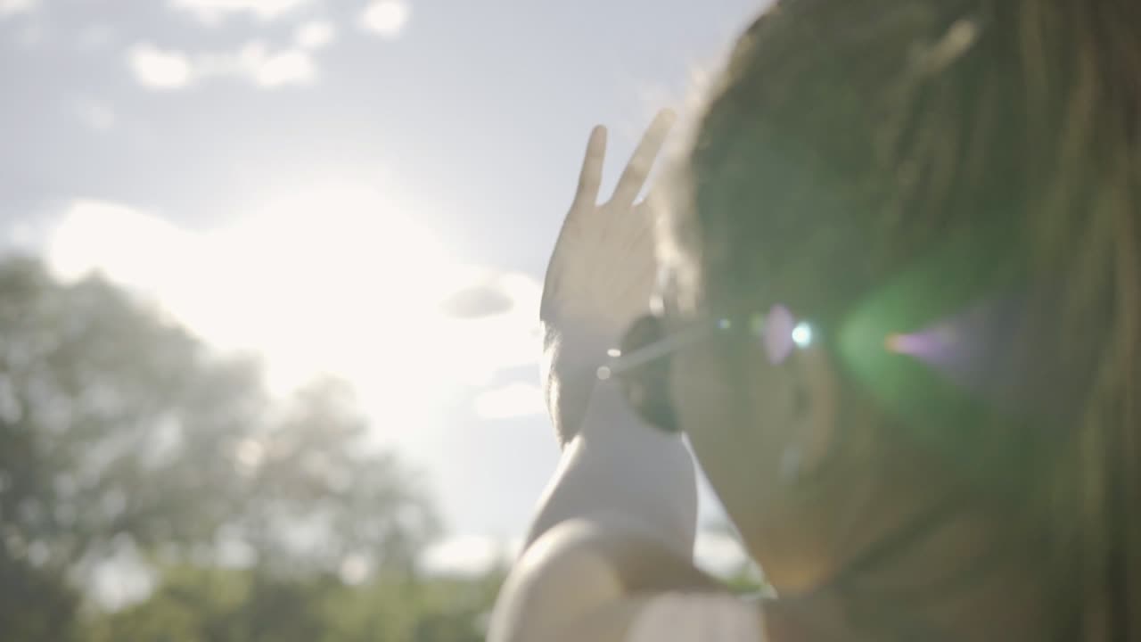 아들을 바라보며 손으로 아들에게서 자신을 숨기는 여자의 가까운 뒷면. 드레드를 가진 젊은 여성이 놀고 있습니다.